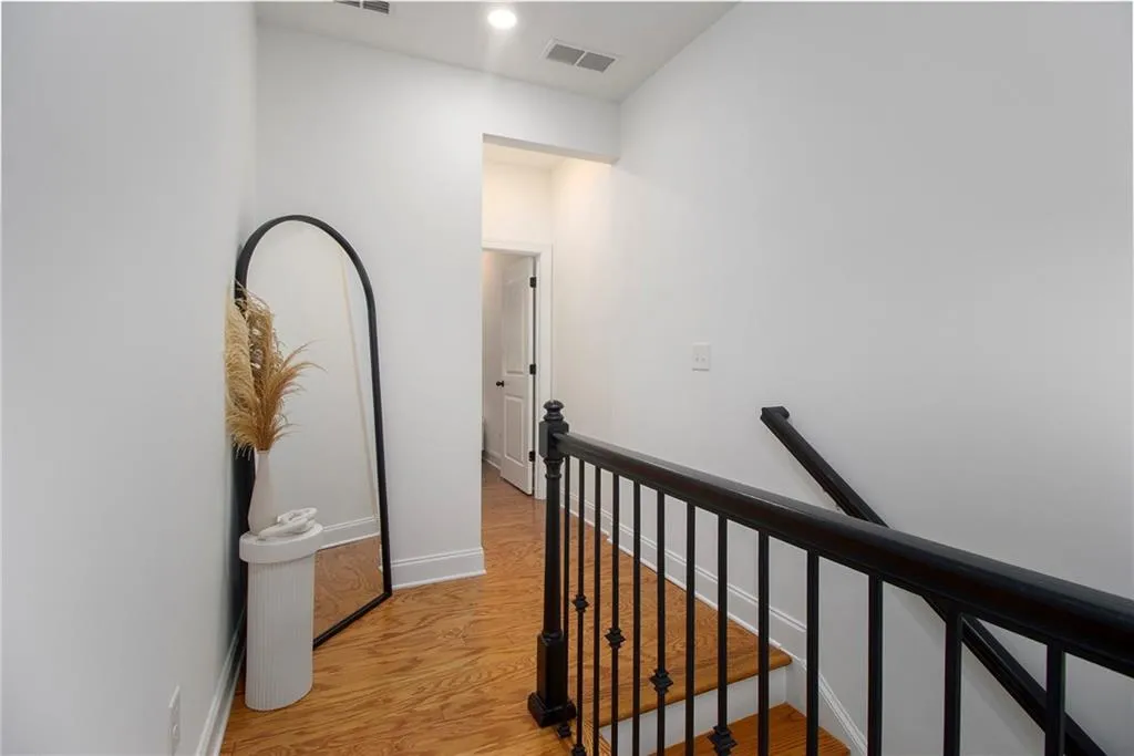 Corridor featuring an upstairs landing and light wood-style flooring
