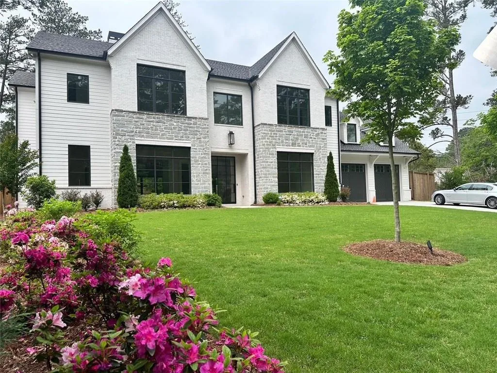 View of front of house with stone siding, a garage, driveway, and roof with shingles
