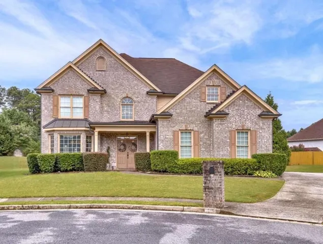 Brick exterior with multiple gables, covered entry, bay window, and a concrete driveway