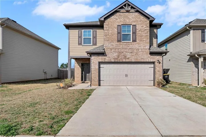 Craftsman-style home featuring brick siding, a front yard, concrete driveway, and a garage