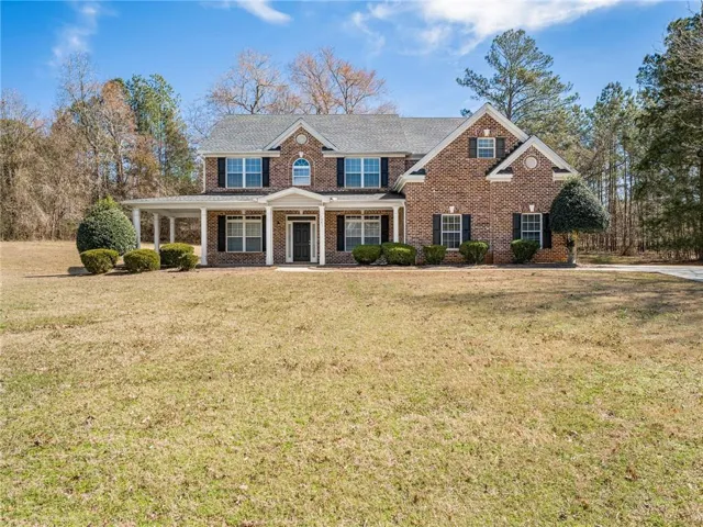 View of front of property featuring covered porch, brick siding, and a front lawn