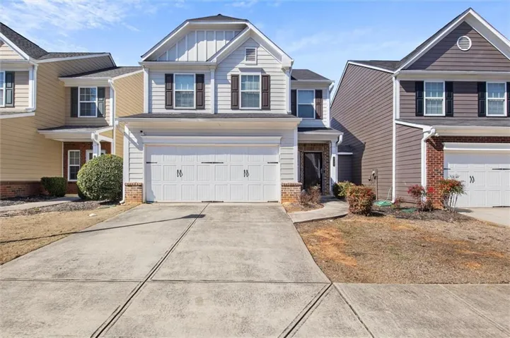Two-story residence featuring light siding, dark shutters, and a two-car garage
