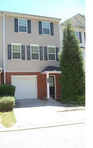 Brick and siding exterior with dark shutters, attached garage, and a covered entry