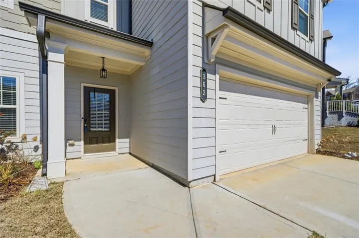 Covered entry with an overhead light fixture, paneled front door with glass inserts, and an attached two-car garage