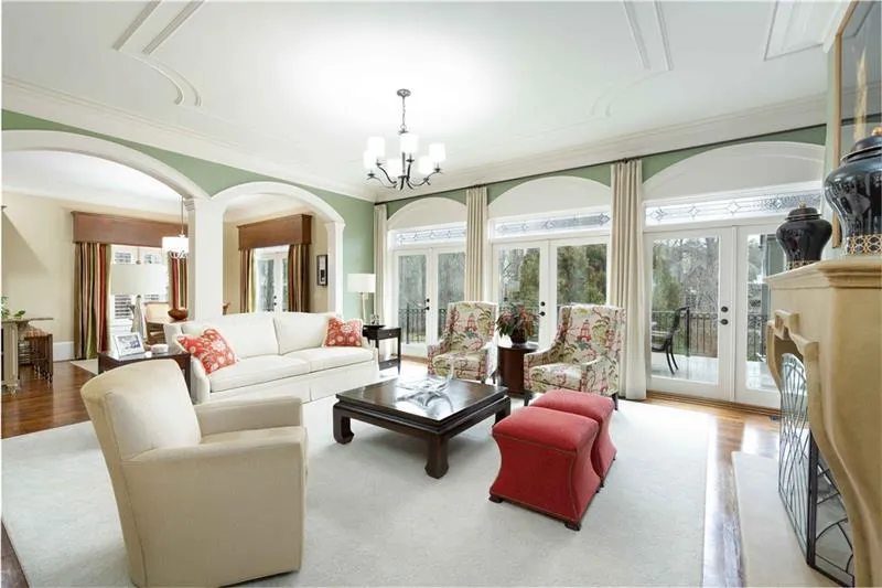 Living room with french doors, crown molding, a notable chandelier, light hardwood / wood-style flooring, and decorative columns