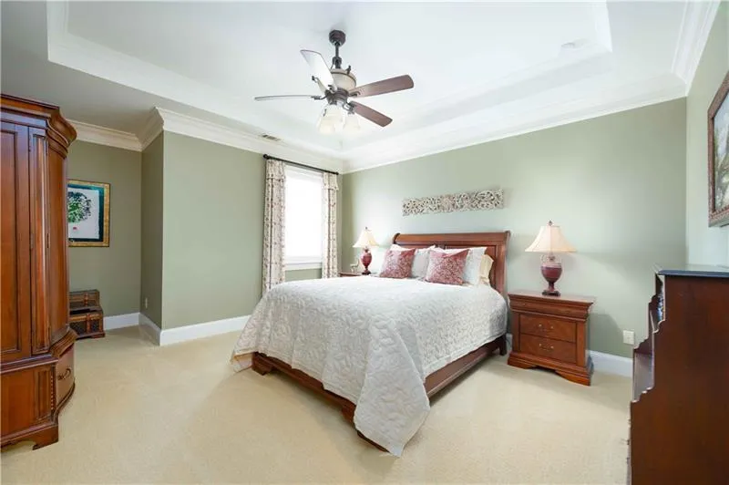 Bedroom featuring ceiling fan, crown molding, light carpet, and a raised ceiling