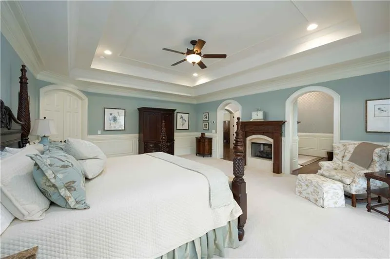 Carpeted bedroom with crown molding, ceiling fan, and a raised ceiling