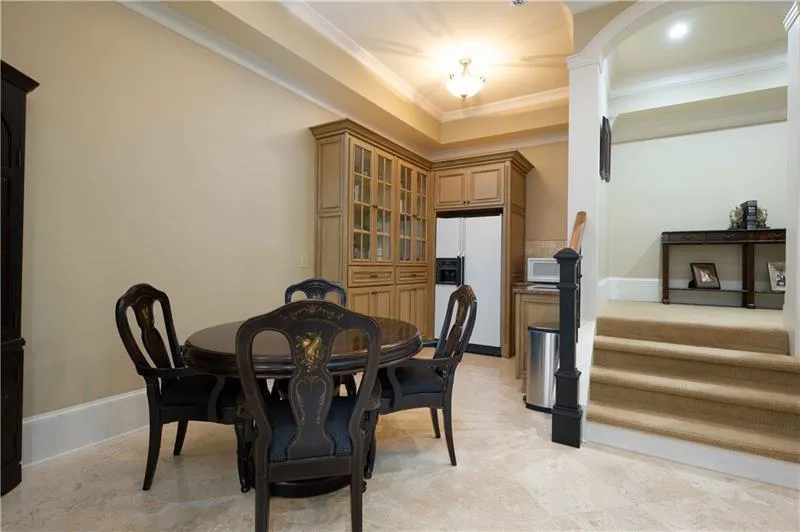 Tiled dining area with crown molding, a raised ceiling, and ornate columns