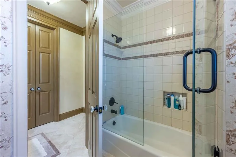 Bathroom featuring bath / shower combo with glass door, tile floors, and crown molding