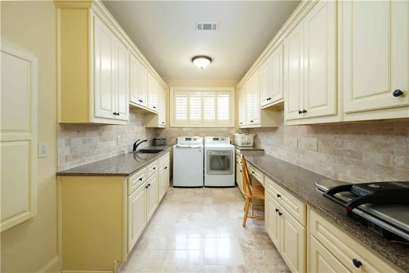 Kitchen featuring backsplash, independent washer and dryer, light tile floors, and sink