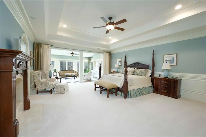 Bedroom featuring a raised ceiling, light colored carpet, access to exterior, ceiling fan, and ornamental molding