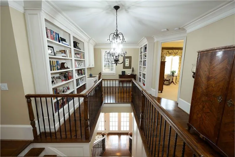 Hallway with dark hardwood / wood-style flooring, ornamental molding, plenty of natural light, and a chandelier
