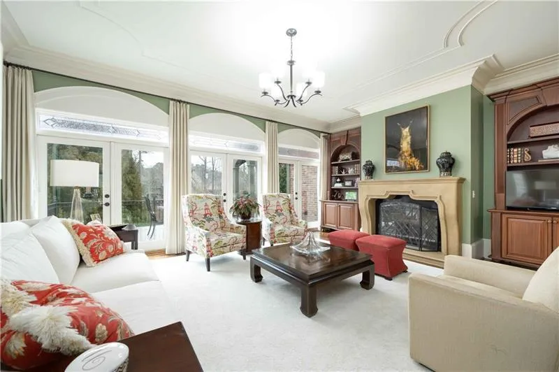 Living room with built in shelves, light colored carpet, french doors, and a healthy amount of sunlight