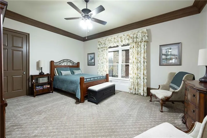 Carpeted bedroom with ceiling fan and ornamental molding