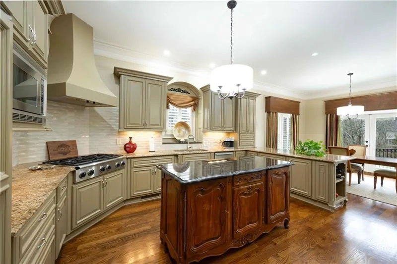 Kitchen with a kitchen island, premium range hood, dark stone countertops, decorative light fixtures, and dark hardwood / wood-style floors