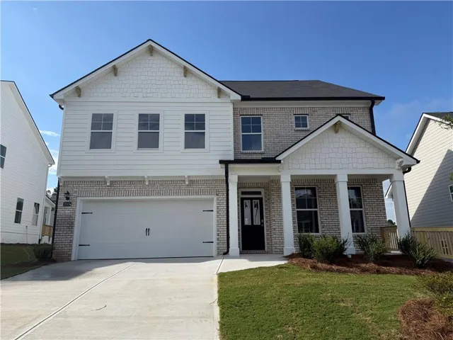 Two-story residence featuring a covered entry, an attached two-car garage, brick and siding exterior, and a concrete driveway