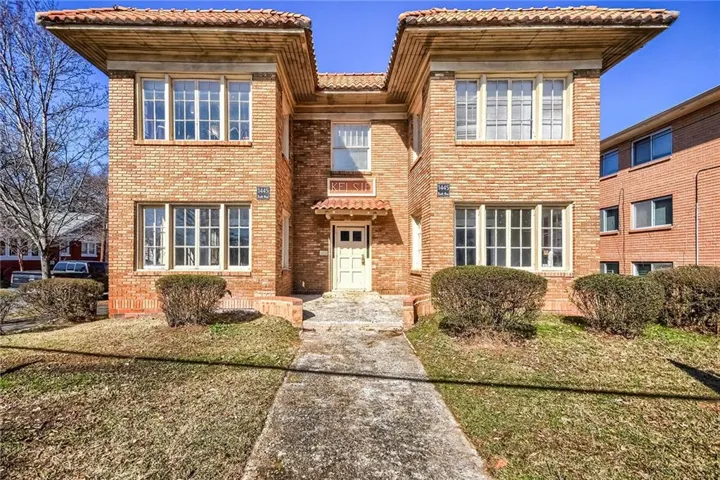 symmetrical façade with paired multi-pane windows, decorative tile roofing, and a centered entrance portico
