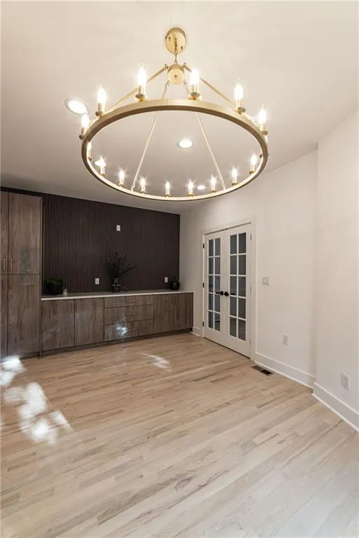 Unfurnished living room with wood finished floors, a chandelier, french doors, and recessed lighting