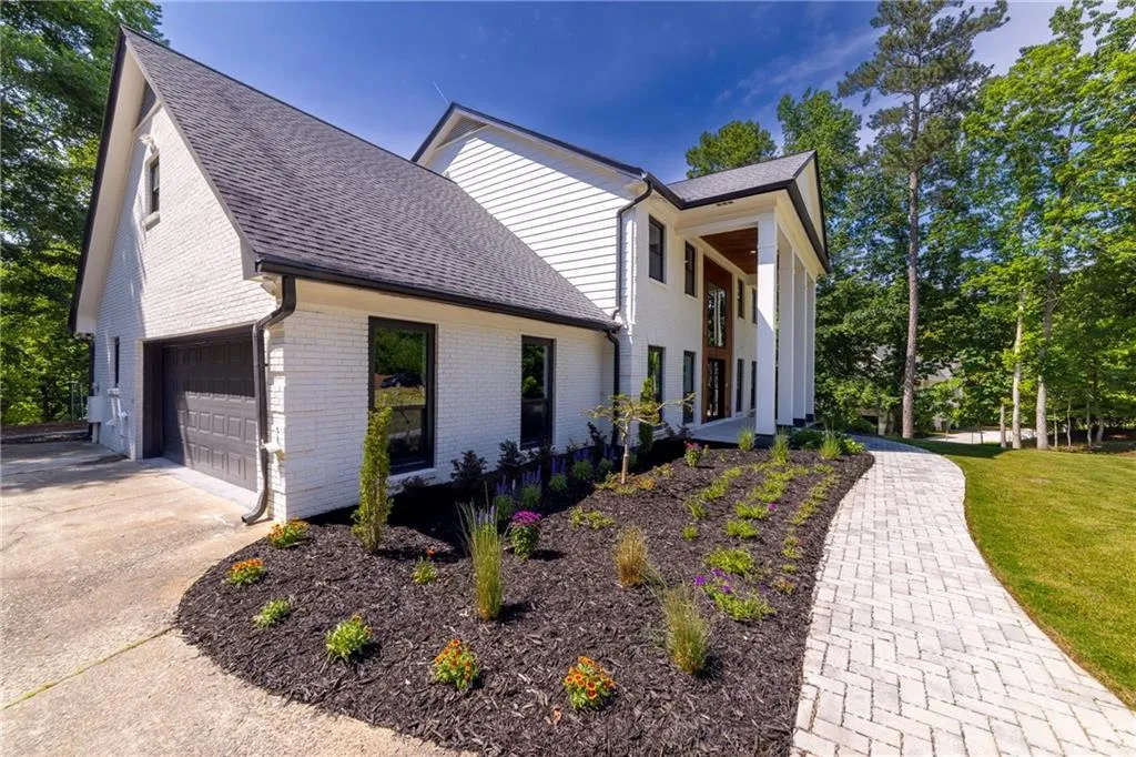 View of property exterior featuring brick siding, roof with shingles, and concrete driveway