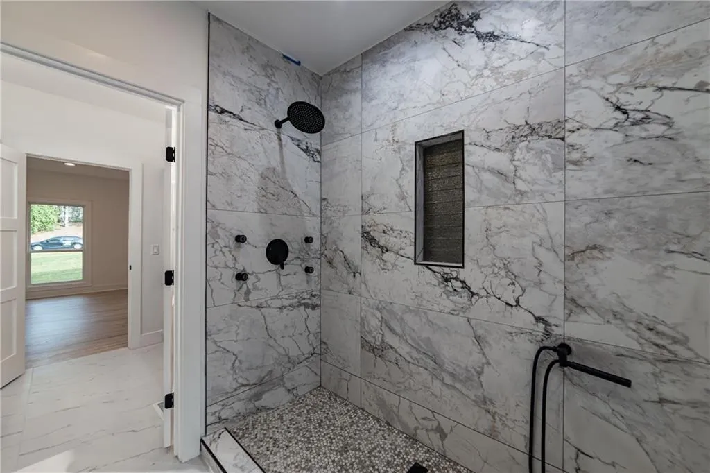 Full bath with marble finish flooring and a marble finish shower