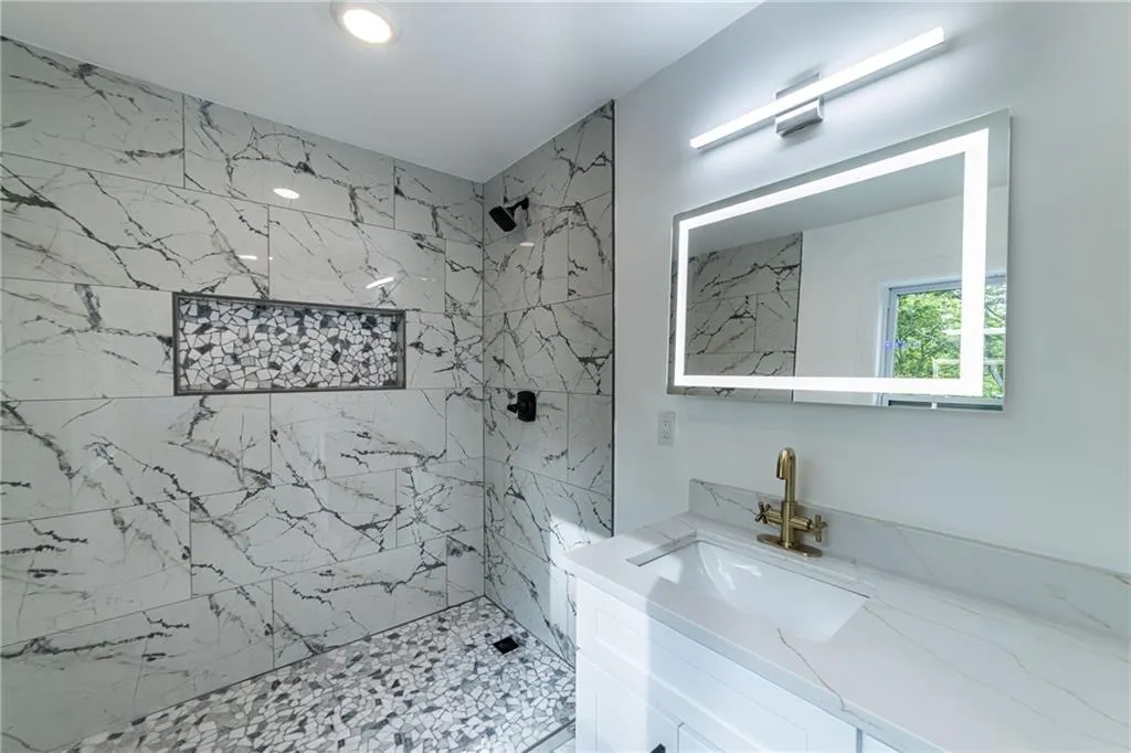 Full bath with a marble finish shower and vanity