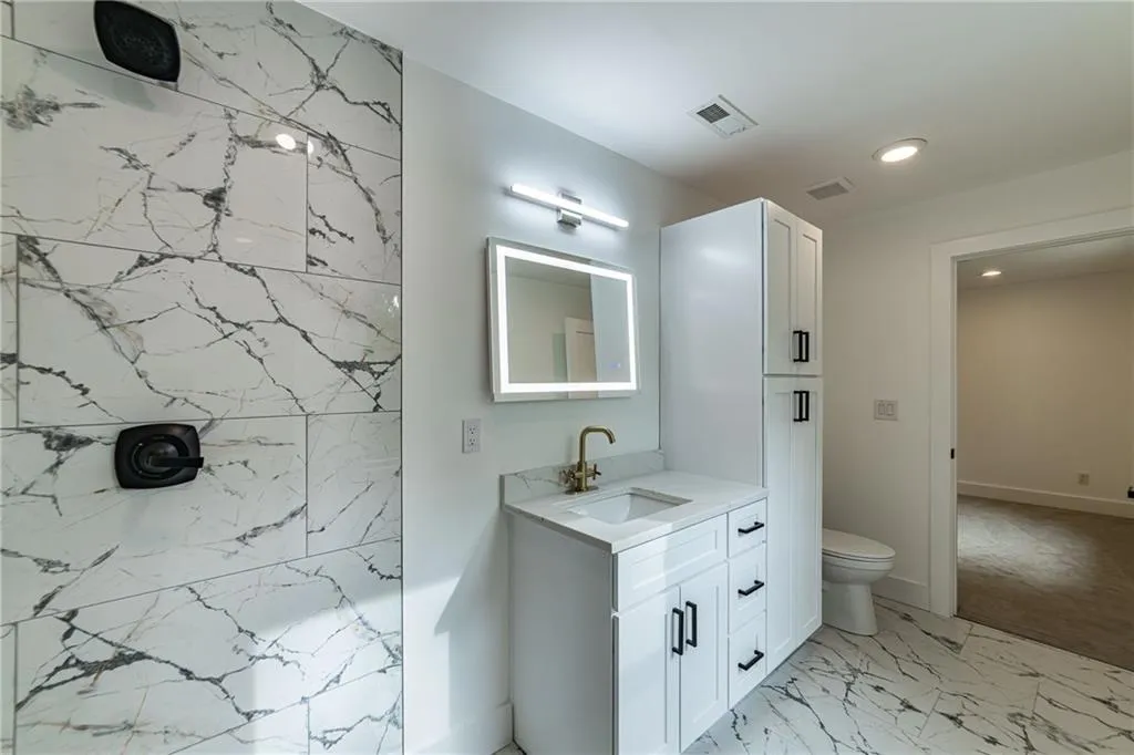 Bathroom with vanity, recessed lighting, marble finish floors, and a shower