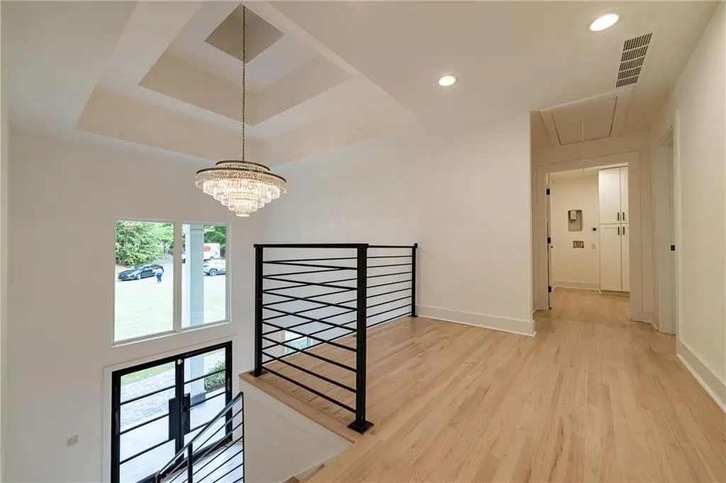 Hallway featuring an upstairs landing, attic access, light wood-style flooring, a raised ceiling, and recessed lighting