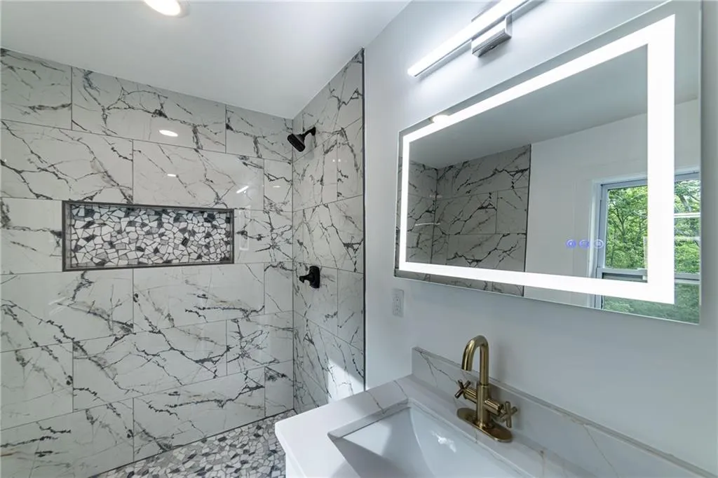 Bathroom with a marble finish shower and vanity
