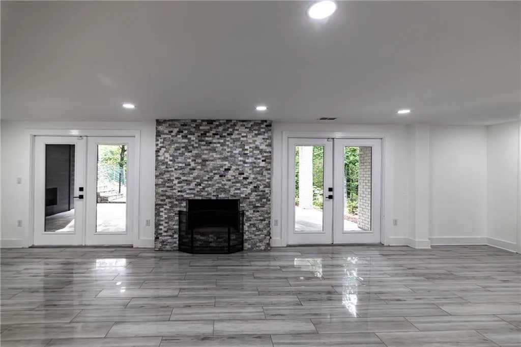 Unfurnished living room with french doors, recessed lighting, healthy amount of natural light, a stone fireplace, and wood finish floors