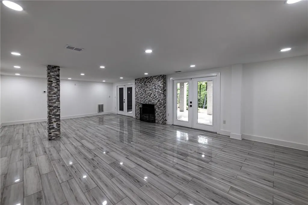 Unfurnished living room with recessed lighting, french doors, wood tiled floors, and a large fireplace