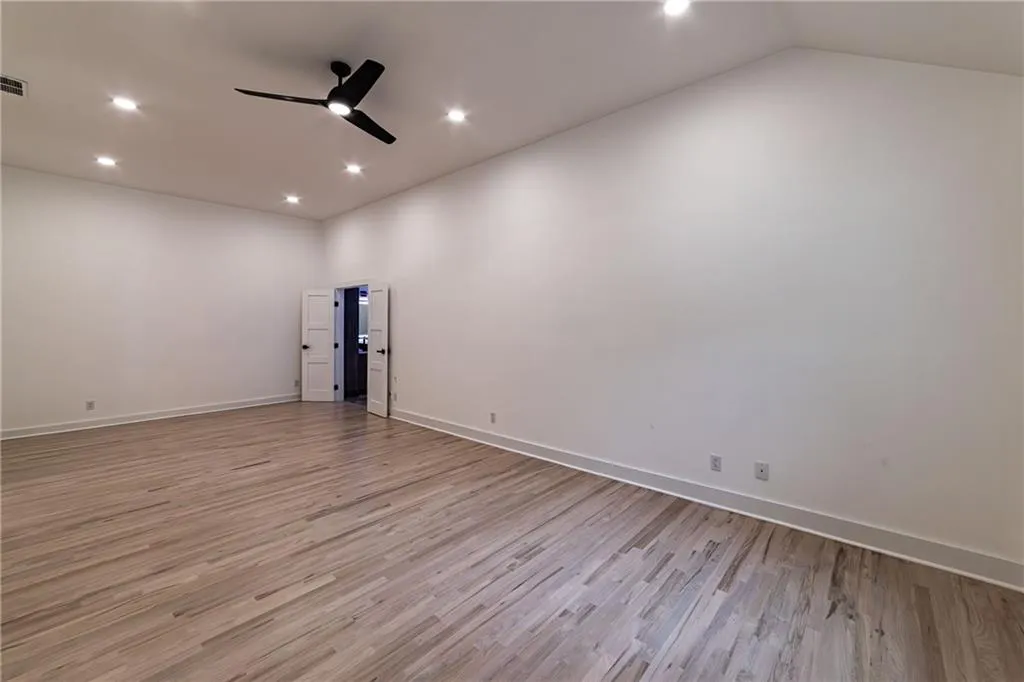 Spare room with light wood-style floors, a ceiling fan, recessed lighting, and vaulted ceiling