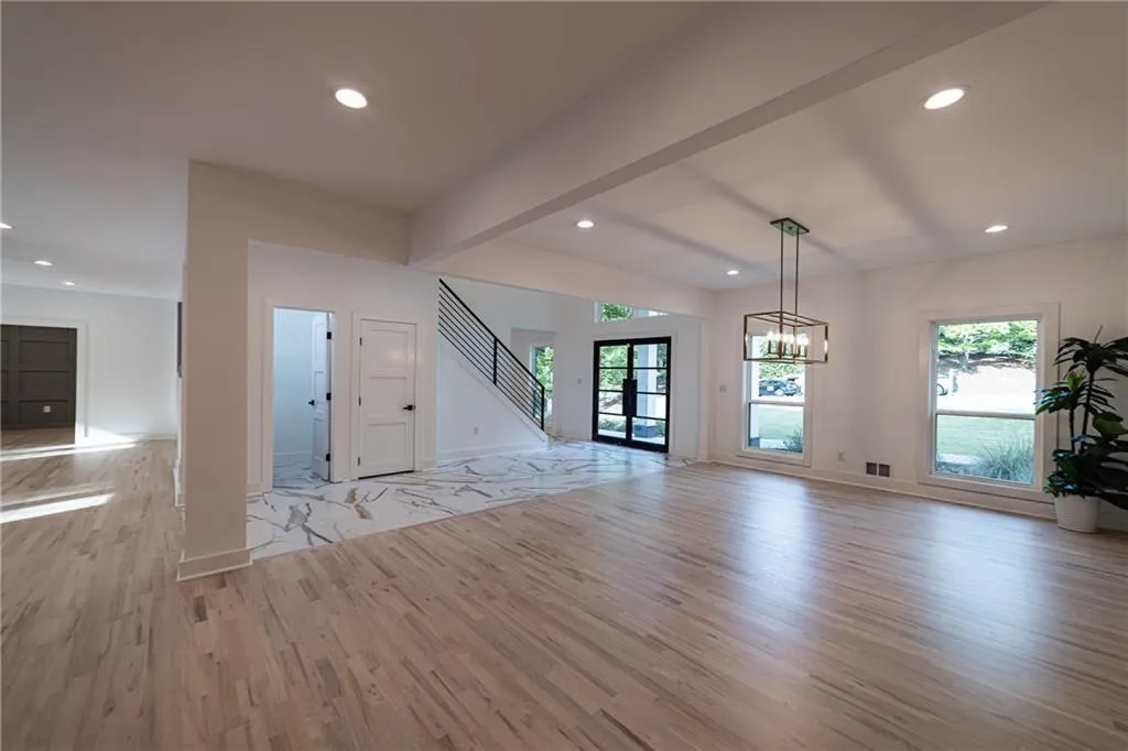 Unfurnished living room with recessed lighting, light wood-type flooring, a chandelier, and beamed ceiling