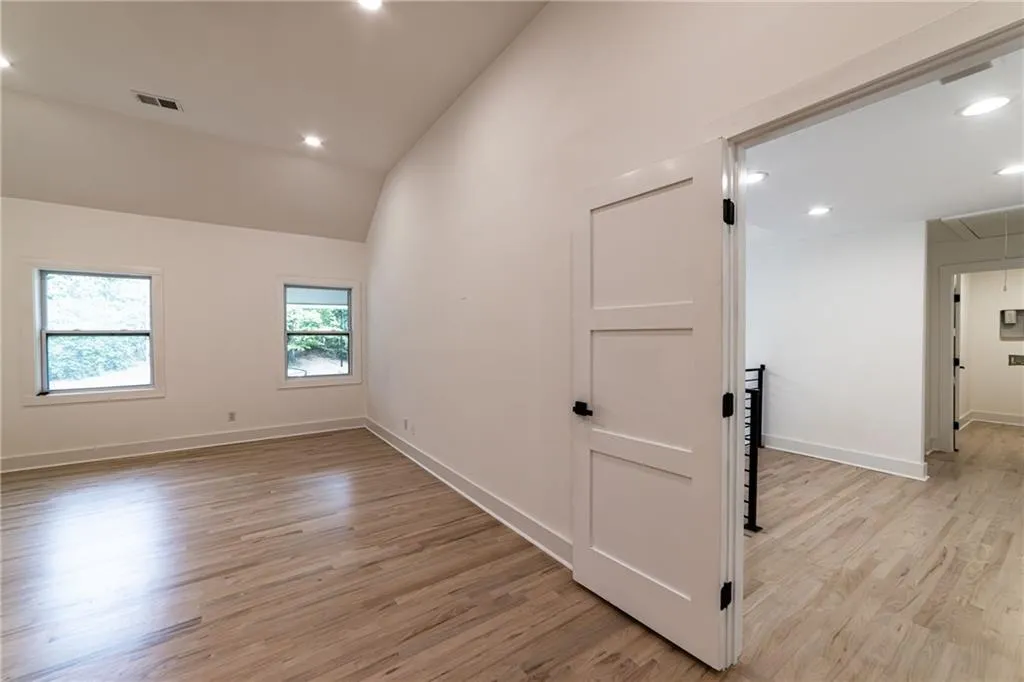 Unfurnished room featuring attic access, recessed lighting, light wood-type flooring, and high vaulted ceiling