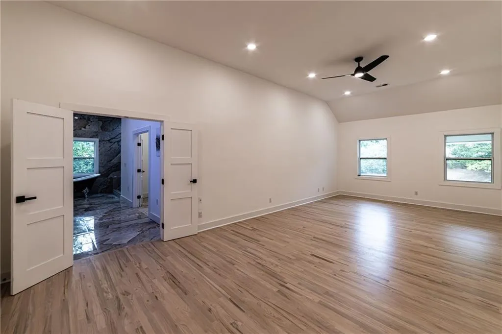 Spare room featuring light wood finished floors, ceiling fan, recessed lighting, and high vaulted ceiling