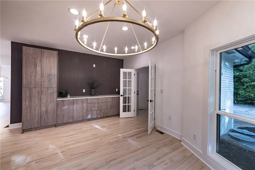 Unfurnished dining area featuring a chandelier, light wood-style floors, french doors, and recessed lighting