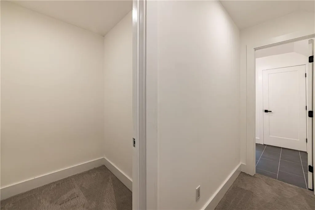Hallway featuring dark tile patterned floors and dark colored carpet