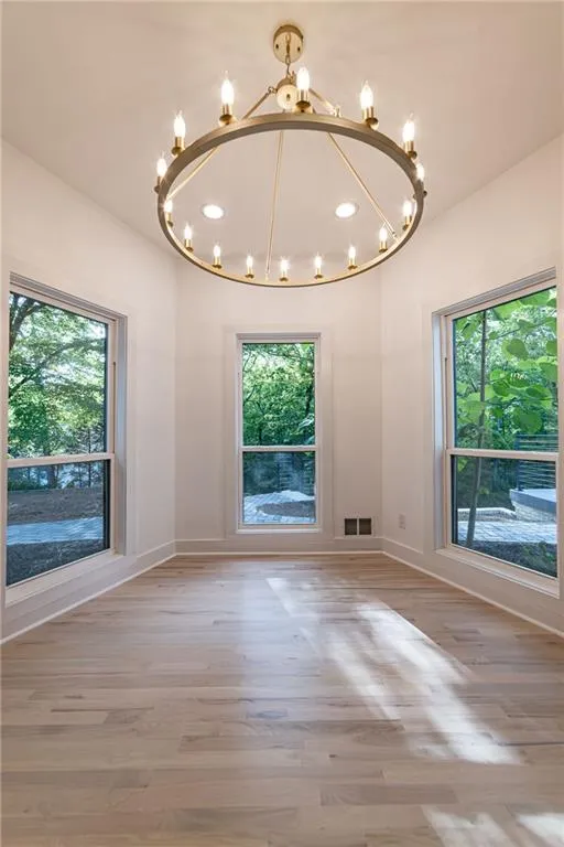 Unfurnished dining area featuring wood finished floors, recessed lighting, and a chandelier