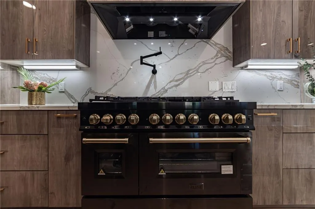 Kitchen with ventilation hood, double oven range, modern cabinets, and tasteful backsplash