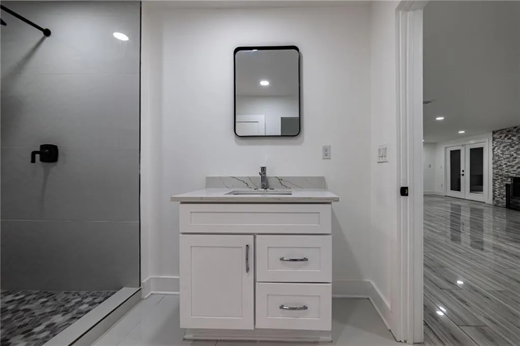 Bathroom featuring a tile shower, vanity, and recessed lighting