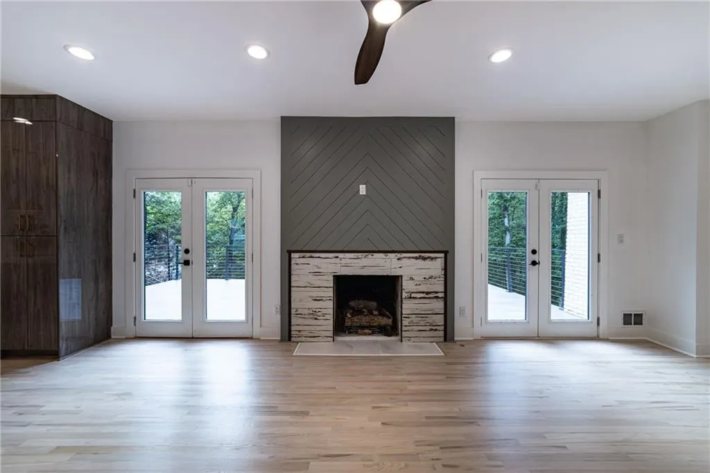 Unfurnished living room featuring french doors, light wood finished floors, recessed lighting, a fireplace, and a ceiling fan