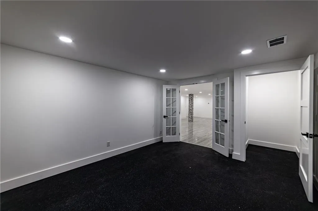Empty room featuring french doors, recessed lighting, and dark colored carpet