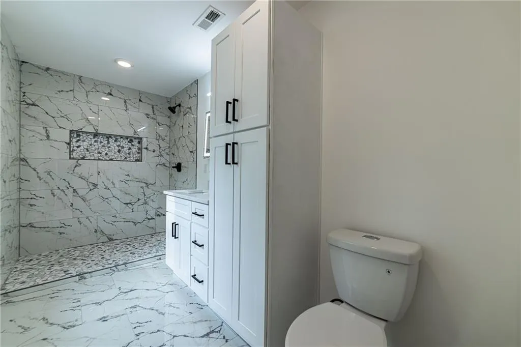 Bathroom featuring marble finish flooring, a marble finish shower, vanity, and recessed lighting