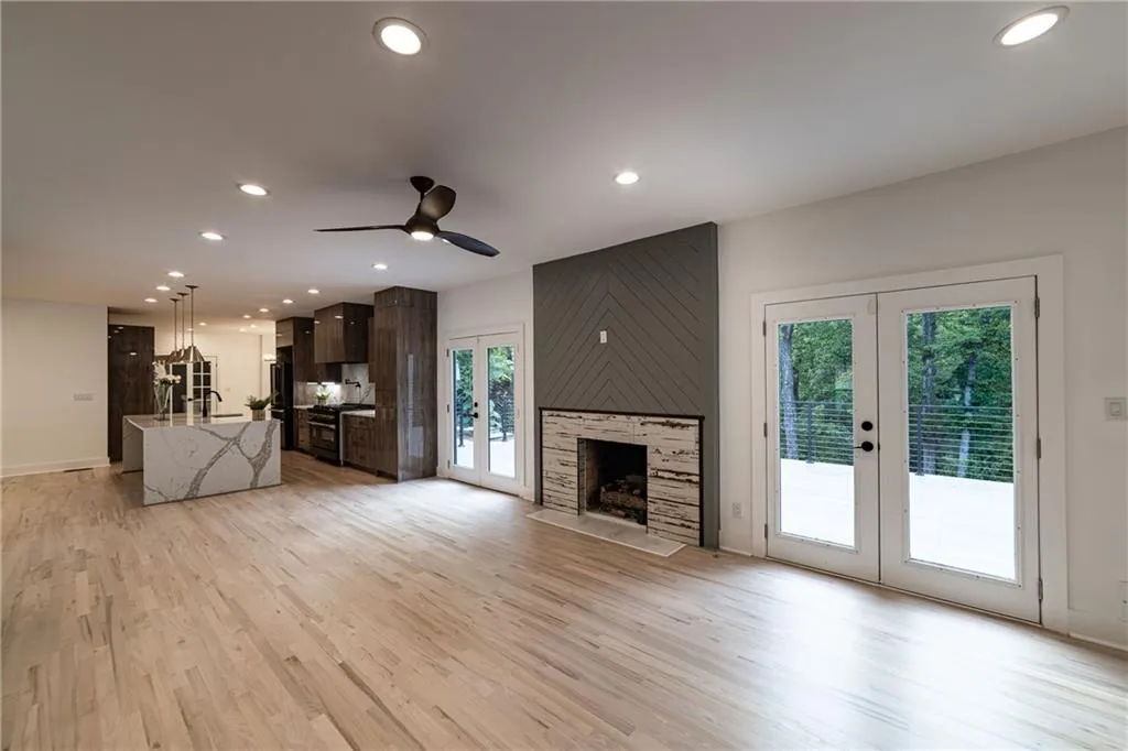 Unfurnished living room with french doors, recessed lighting, light wood finished floors, ceiling fan, and a large fireplace