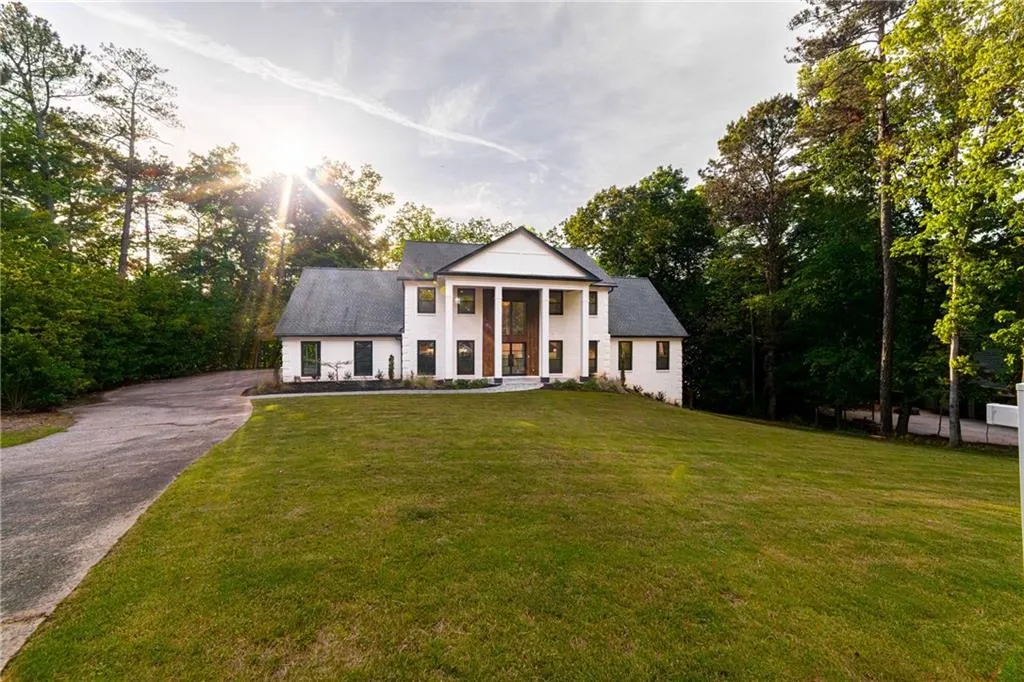 Greek revival house with a front yard, asphalt driveway, and view of scattered trees