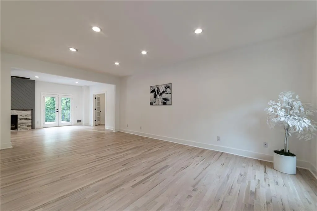 Unfurnished living room featuring french doors, light wood-style floors, recessed lighting, and a large fireplace