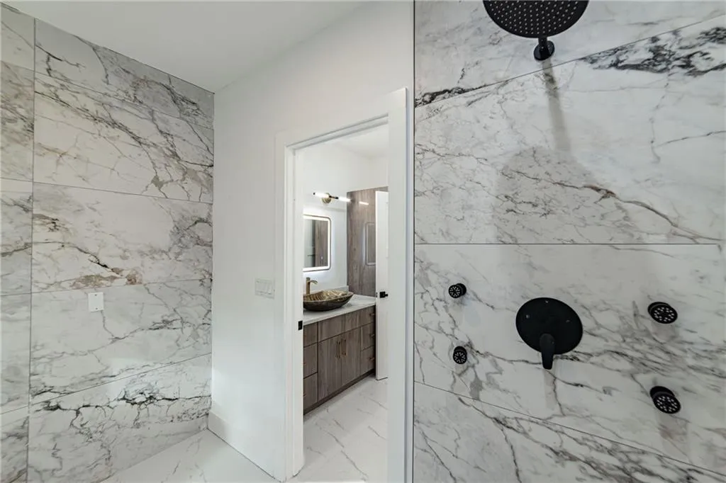 Full bath with marble look tile flooring, a marble finish shower, vanity, and tile walls