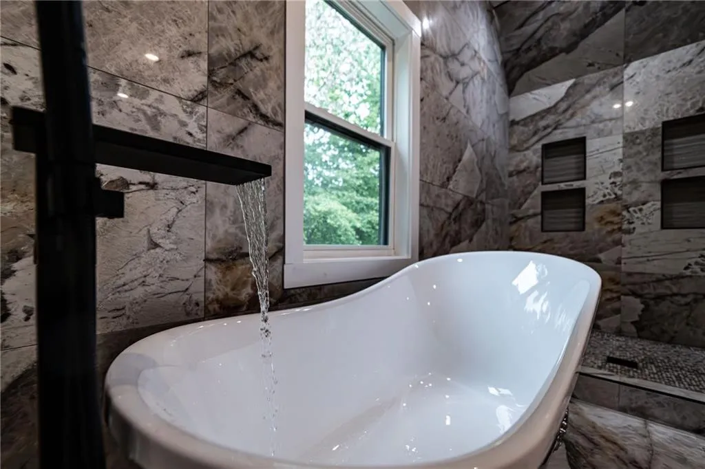 Full bathroom featuring a soaking tub and tile walls
