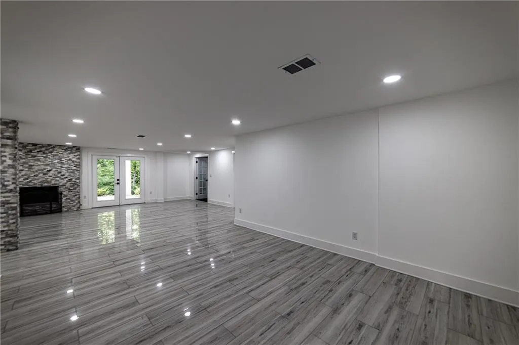 Unfurnished living room with french doors, recessed lighting, a stone fireplace, and wood finished floors