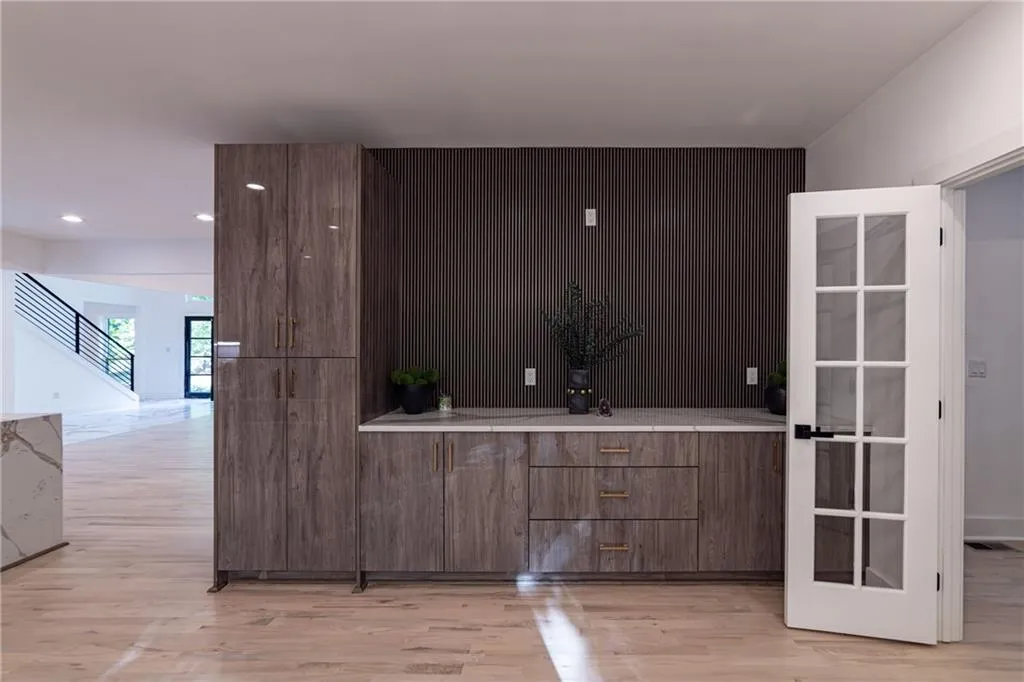 Bar area with light wood finished floors, stairway, and recessed lighting