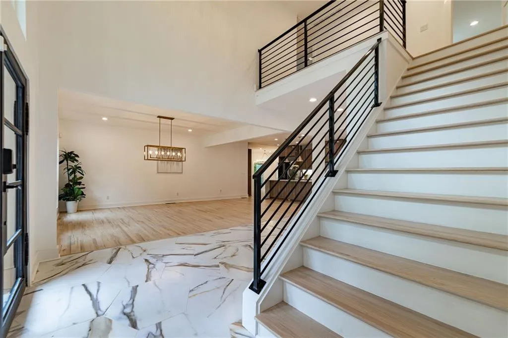 Stairway featuring marble tiled floors, recessed lighting, and a high ceiling